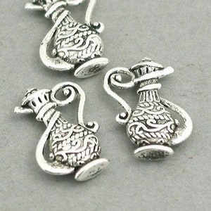 May include: Three silver-toned metal charms shaped like ornate teapots with intricate designs. The charms are perfect for adding a touch of vintage elegance to jewelry or crafts.