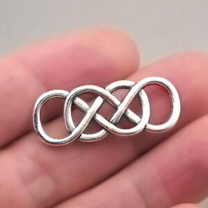 May include: Silver infinity knot charm with a smooth, polished finish. The knot is a continuous loop, symbolising eternity and endless love.