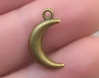 May include: A gold-toned crescent moon charm with a loop for attaching to jewelry or other crafts.