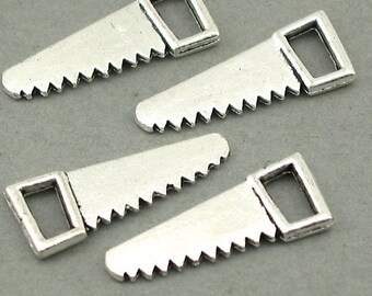 May include: Four silver-toned metal charms shaped like hand saws. Each charm features a triangular blade with a serrated edge and a rectangular handle loop at the wider end. The metal has a matte finish with visible detailing on the teeth.