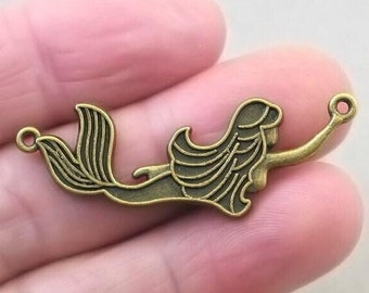 May include: Antique bronze mermaid charm with a detailed design. The charm has two jump rings for attaching to jewellery or other crafts.