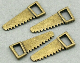 May include: Four antique bronze-colored metal charms shaped like hand saws. Each charm features a rectangular handle at one end and a serrated blade edge. The metal has a matte, weathered finish with visible texture across the surface of each piece.