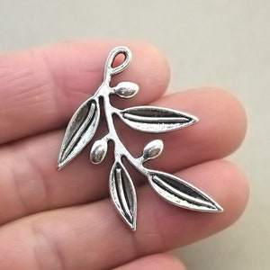 May include: Silver-toned metal charm shaped like an olive branch with leaves and berries.