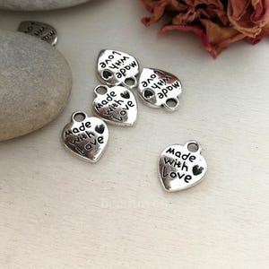 May include: Five silver heart-shaped charms with the text "Made with Love" on each charm.