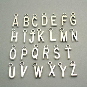 May include: Silver alphabet letter charms, A through Z, with a loop for attaching to jewelry or crafts.