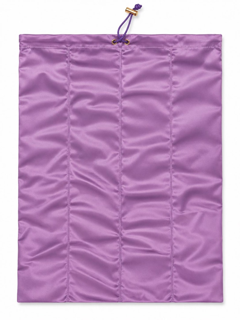 May include: A rectangular purple satin drawstring bag featuring vertical quilted stitching. The top opening is secured with a purple cord threaded through gold-toned metal eyelets, finished with a small gold-toned cylindrical toggle at the end.