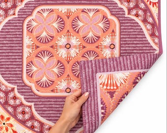 May include: A rectangular mat featuring a repeating floral pattern in shades of coral, pink, and deep burgundy. The design includes circular motifs with radiating petals and a border with a textured, dashed line pattern on a dark background.