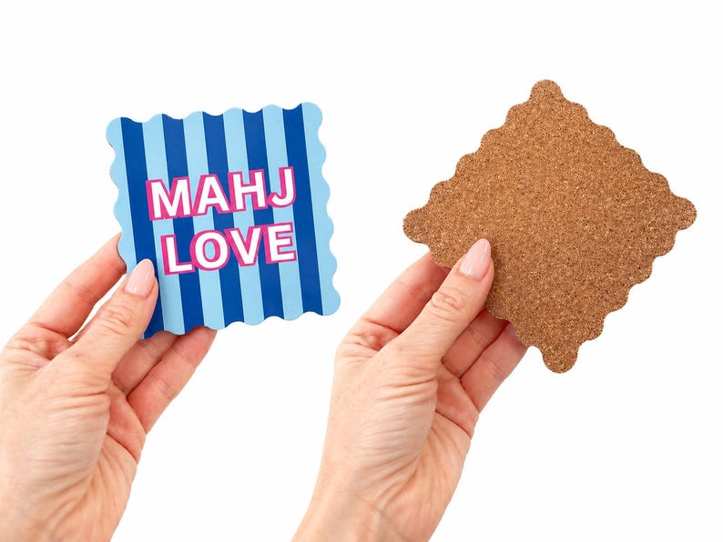May include: A square coaster with scalloped edges featuring vertical light and dark blue stripes and the text MAHJ LOVE in pink letters. The reverse side of the coaster is made of brown cork with a matching scalloped edge design.