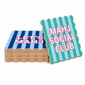 May include: A stack of square cork coasters with wavy edges. The top coaster features teal and light blue vertical stripes with the pink text MAHJ SOCIAL CLUB. The lower coasters have dark blue and light blue stripes with the pink text LET'S MAHJ.