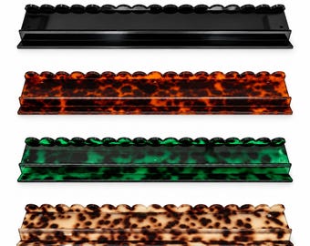 May include: Four rectangular wall shelves with scalloped top edges. The top shelf is solid black, the second is dark brown tortoiseshell, the third is green tortoiseshell, and the bottom shelf is a light beige tortoiseshell pattern.