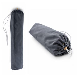 May include: A cylindrical dark gray velvet drawstring bag featuring a soft fabric texture, a white cord closure, and a small metallic gold-toned bead at the end of the drawstring. The bag is shown in both a vertical upright position and a horizontal orientation.
