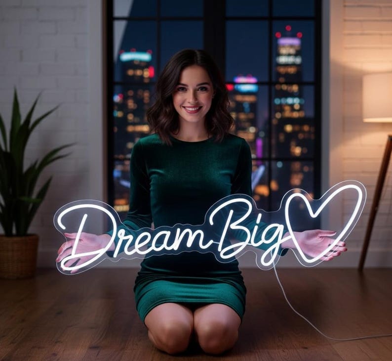 May include: A white neon sign featuring the cursive text Dream Big followed by a heart outline. The sign is constructed from flexible tubing that emits a bright white glow, creating a clear and legible message against the dark background.