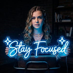 May include: A blue neon sign with the words "Stay Focused" in a cursive font. The sign is surrounded by decorative star shapes. The sign is held up in front of a person.