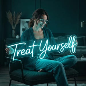 May include: A bright teal neon sign featuring the cursive text Treat Yourself. The sign is constructed with a clear acrylic backing that follows the contour of the illuminated lettering, creating a glowing display of light in a script font.