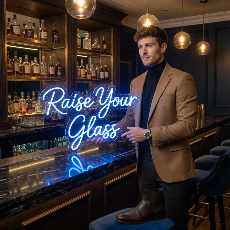 May include: A bright blue neon sign with the text "Raise Your Glass" in a cursive script font. The sign is illuminated and features a clear acrylic backing, designed to be displayed in a bar or lounge setting to create a vibrant atmosphere.