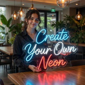 May include: A custom neon sign mounted on a clear, wavy acrylic backing. The sign features the text "Create Your Own Neon" in a cursive font, with "Create" in blue, "Your Own" in white, and "Neon" in red, illuminated by bright LED tubing.