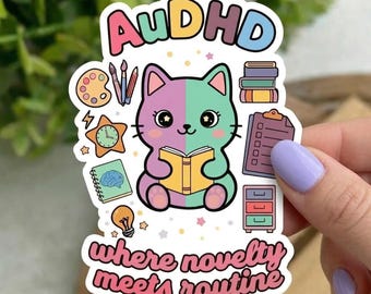 May include: A colorful sticker featuring a split-faced cat reading a book, with the text "AuDHD" and "where novelty meets routine." The sticker includes illustrations of art supplies, books, a brain, a clock, and a checklist.