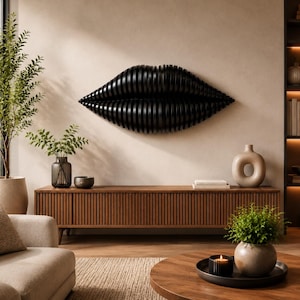 May include: A large, black, three-dimensional lip sculpture hangs on a neutral-colored wall. Below, a long, wooden media console with vertical grooves holds decorative items. A round coffee table and a potted plant are in the foreground.