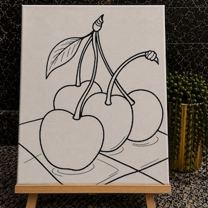 May include: A white canvas featuring a black line art illustration of three cherries with stems and a single leaf. The cherries are positioned on a surface with a grid pattern. The canvas is displayed on a small wooden easel stand.