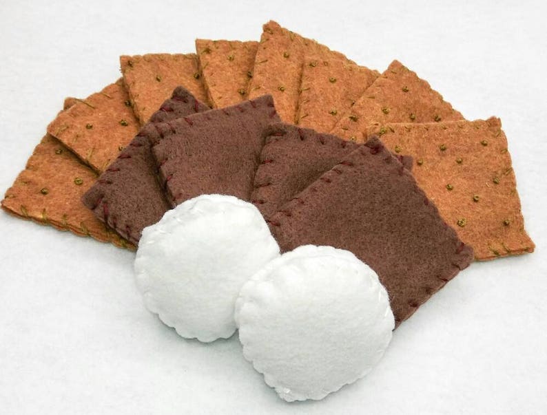K&ouml;nnte beinhalten: Ein Set aus Filz-Graham-Crackern, Schokoladenquadraten und Marshmallows f&uuml;r ein Spielzeug-S'mores-Bastelprojekt.