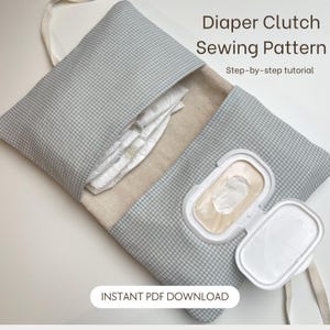Może przedstawiać: Otwarta kopertówka na pieluchy z szarym zewnętrzem w kratkę i beżowym wnętrzem, zawierająca pieluchy i biały pojemnik na chusteczki. Widoczny tekst "Diaper Clutch Sewing Pattern" i "Instant PDF Download".