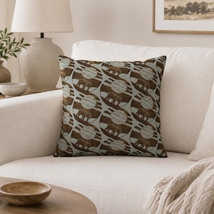 May include: A square throw pillow featuring a repeating pattern of circular motifs. Each circle contains a dark brown silhouette of an elephant walking against a background of horizontal stripes and a large, pale circular sun or moon shape.