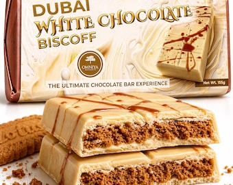 Puede incluir: Una barra rectangular de chocolate blanco Dubai Biscoff con un envoltorio color crema que presenta el texto "DUBAI WHITE CHOCOLATE BISCOFF" y "OMNIYA DESSERTS". Dos trozos apilados de la barra revelan un relleno marrón y texturizado.