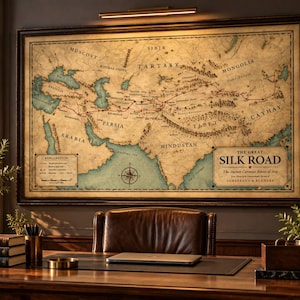 May include: A large, rectangular, framed wall map titled The Great Silk Road, The Ancient Caravan Routes of Asia. The map features a vintage, aged-paper aesthetic with detailed geographical labels, red route lines, and a compass rose.