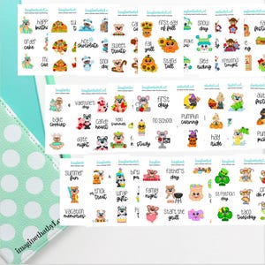 May include: A sheet of decorative stickers with various themed illustrations and text. Designs include bears, pumpkins, and seasonal phrases like "First Day of Fall" and "Valentine's Day." The stickers are colorful and suitable for planners.