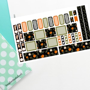 May include: A sheet of planner stickers with a black, green, and orange floral pattern. The stickers include boxes, circles, and flags. The text "Tues", "Wed", "Thu", "Fri", "Sat", "Sun", and "Mon" are visible on the sheet.