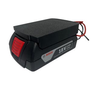 Op de afbeelding: Zwarte en rode Bosch 18V 2.0Ah Li-ion batterij. De batterij heeft een zwarte behuizing met een rode ontgrendelingsknop en een zwarte schuimrubberen bovenkant. Het Bosch-logo is zichtbaar.