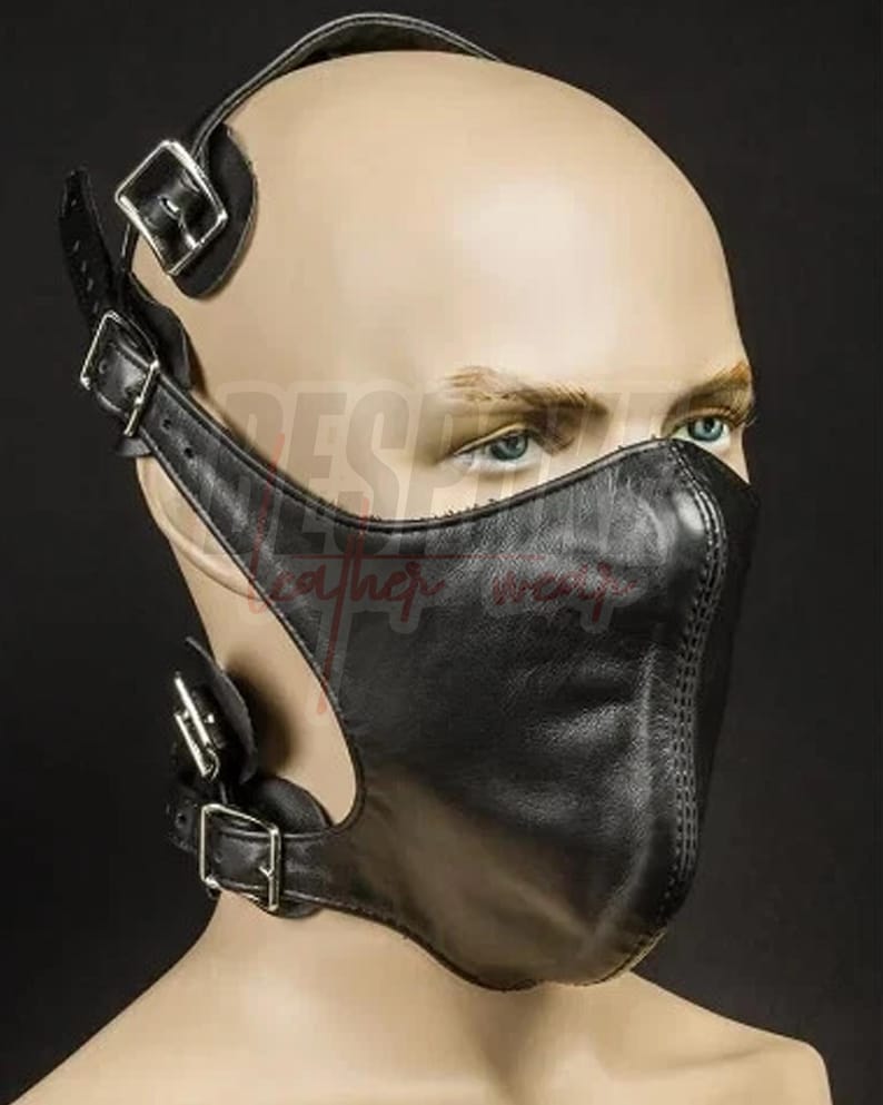 Puede incluir: M&aacute;scara facial de cuero negro con correas ajustables y hebillas met&aacute;licas. La m&aacute;scara cubre la nariz y la boca, con un dise&ntilde;o cosido en la parte delantera. Tiene una correa sobre la cabeza y alrededor del cuello.