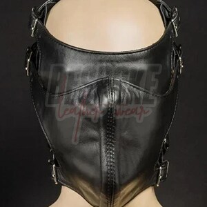 Puede incluir: Una m&aacute;scara de cuero negro con m&uacute;ltiples correas y hebillas ajustables. La m&aacute;scara cubre la parte inferior de la cara y presenta una costura cosida en el centro. El texto "REBKE leather wear" es visible en la m&aacute;scara.