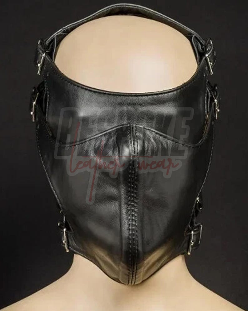 Puede incluir: Una m&aacute;scara de cuero negro con m&uacute;ltiples correas y hebillas ajustables. La m&aacute;scara cubre la parte inferior de la cara y presenta una costura cosida en el centro. El texto "REBKE leather wear" es visible en la m&aacute;scara.