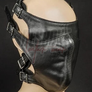 Puede incluir: M&aacute;scara facial de cuero negro con m&uacute;ltiples correas y hebillas plateadas. La m&aacute;scara cubre la nariz y la boca, con cortes alrededor de los ojos y las mejillas. La m&aacute;scara est&aacute; dise&ntilde;ada con una forma contorneada y costuras.