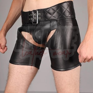 May include: Black leather chaps with a quilted waistband and a large buckle. The chaps have a unique design with open sides and a front panel. The garment is designed for a close fit and is made of a smooth, shiny leather.