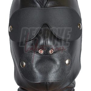 Può includere: Cappuccio in pelle nera con aperture per occhi e bocca, fissato con rivetti metallici. Il cappuccio include una benda e un collare con un anello metallico. Prodotto per giochi di ruolo.