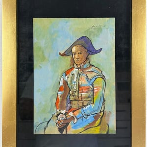 Puede incluir: Una pintura enmarcada que muestra a una figura con un sombrero morado y una chaqueta multicolor en tonos azules, naranjas y amarillos. La figura tiene una tez bronceada y está representada de cintura para arriba. La obra está firmada Picasso arriba.