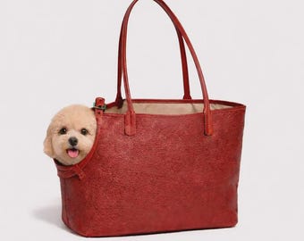 Puede incluir: Un bolso tote rojo texturizado con una abertura lateral para un perro pequeño. El perro es de color marrón claro, con la lengua visible. El bolso tiene dos asas largas.