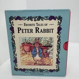 May include: A light blue box set of "Favorite Tales of Peter Rabbit" with illustrations. The cover features a drawing of Peter Rabbit in a blue jacket. The box is decorated with grape vine designs.