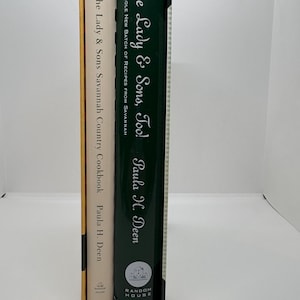 May include: Two cookbooks, "The Lady & Sons, Too!" and "The Lady & Sons Savannah Country Cookbook" by Paula H. Deen, are displayed in a black box. The first book has a green spine with white text, and the second has a beige spine with black text. The Random House logo is visible.