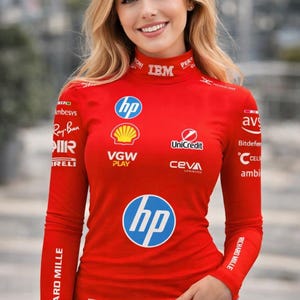 Peut inclure: Un t-shirt rouge à manches longues avec plusieurs logos, dont "hp", "Ray-Ban" et "IBM". Le t-shirt a un col montant et le numéro "16" est visible. La personne qui porte le t-shirt a les cheveux blonds.