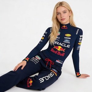 May include: Navy blue long-sleeve top and matching sweatpants with Red Bull and Oracle logos. The top has a mock neck and various sponsor logos. The sweatpants have a red drawstring and the word "ORACLE" printed on the leg.