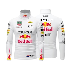 May include: White long-sleeved turtleneck shirt with multiple logos and text. The front features "TAG Heuer", "Oracle", and "Red Bull" branding. The back displays "Sparco", "Oracle", and "Red Bull" logos. Additional logos are on the sleeves.