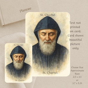 Op de afbeelding: Twee kaarten met een aquarelportret van St. Charbel, een religieuze figuur, in een donkerblauwe capuchon en een lange witte baard. De kaarten hebben de tekst "St. Charbel" erop gedrukt. De geschatte maten zijn 6,35 x 8,89 cm of 9,4 x 13,54 cm.