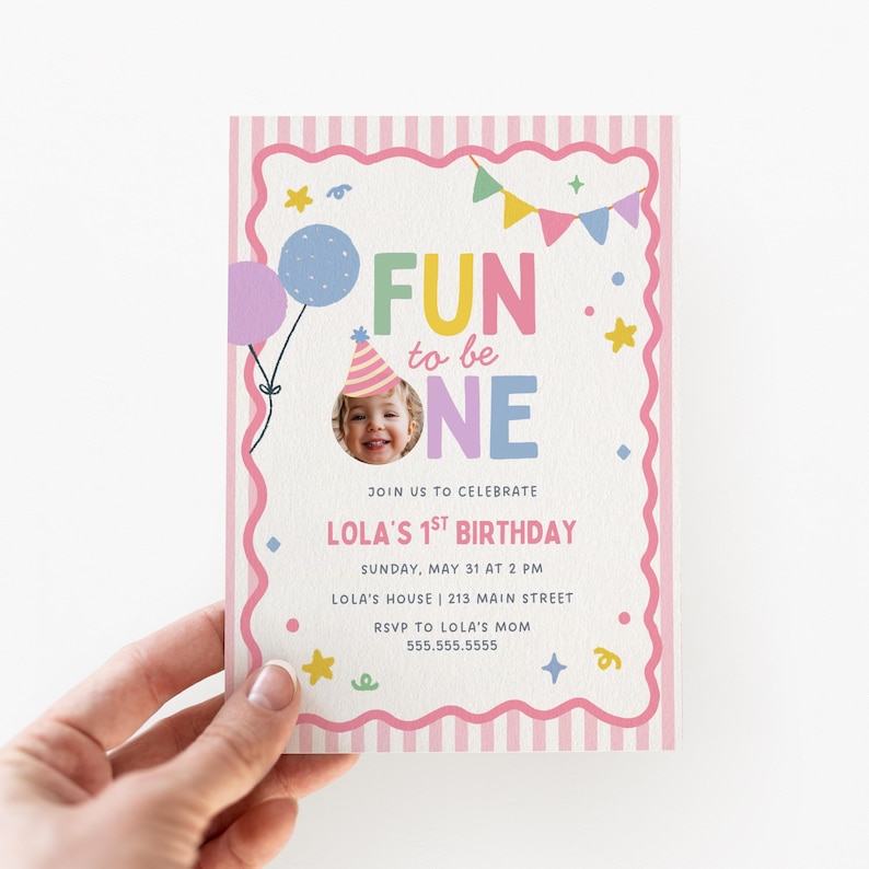 Op de afbeelding: Een rechthoekige verjaardagsuitnodigingskaart met een roze en wit gestreepte rand en een geschulpte omlijsting. De tekst luidt FUN to be ONE, JOIN US TO CELEBRATE LOLA'S 1ST BIRTHDAY, SUNDAY, MAY 31 AT 2 PM, LOLA'S HOUSE, 213 MAIN STREET, RSVP TO LOLA'S MOM 555.555.5555.