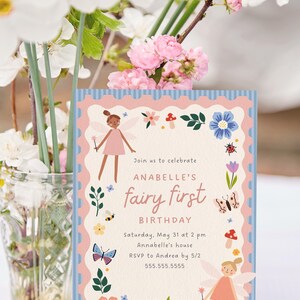 May include: A birthday invitation with a fairy theme. The invitation features a pink and blue scalloped border with illustrations of fairies, flowers, and insects. The text reads "Join us to celebrate ANABELLE'S fairy first BIRTHDAY".