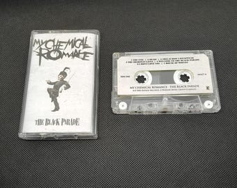 May include: A clear cassette tape and case featuring the album "The Black Parade" by My Chemical Romance. The case has the band's name and album title, along with a marching band figure. The cassette tape is visible next to the case.