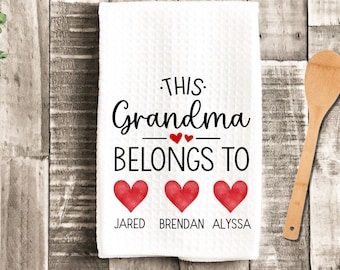 May include: White kitchen towel with the text "This Grandma Belongs To" and three red hearts with the names Jared, Brendan, and Alyssa printed below.
