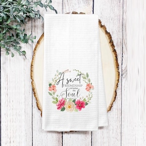 May include: White kitchen towel with a floral wreath design and the text "A sweet friendship refreshes the soul. Proverbs 27:9".